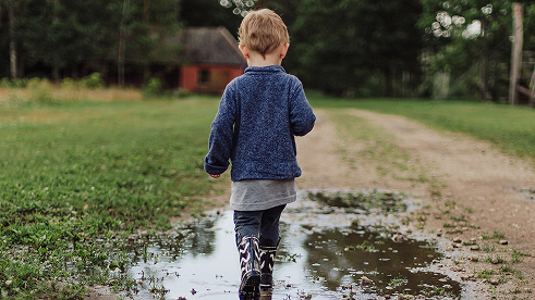 kid running on the wet lawn with boots